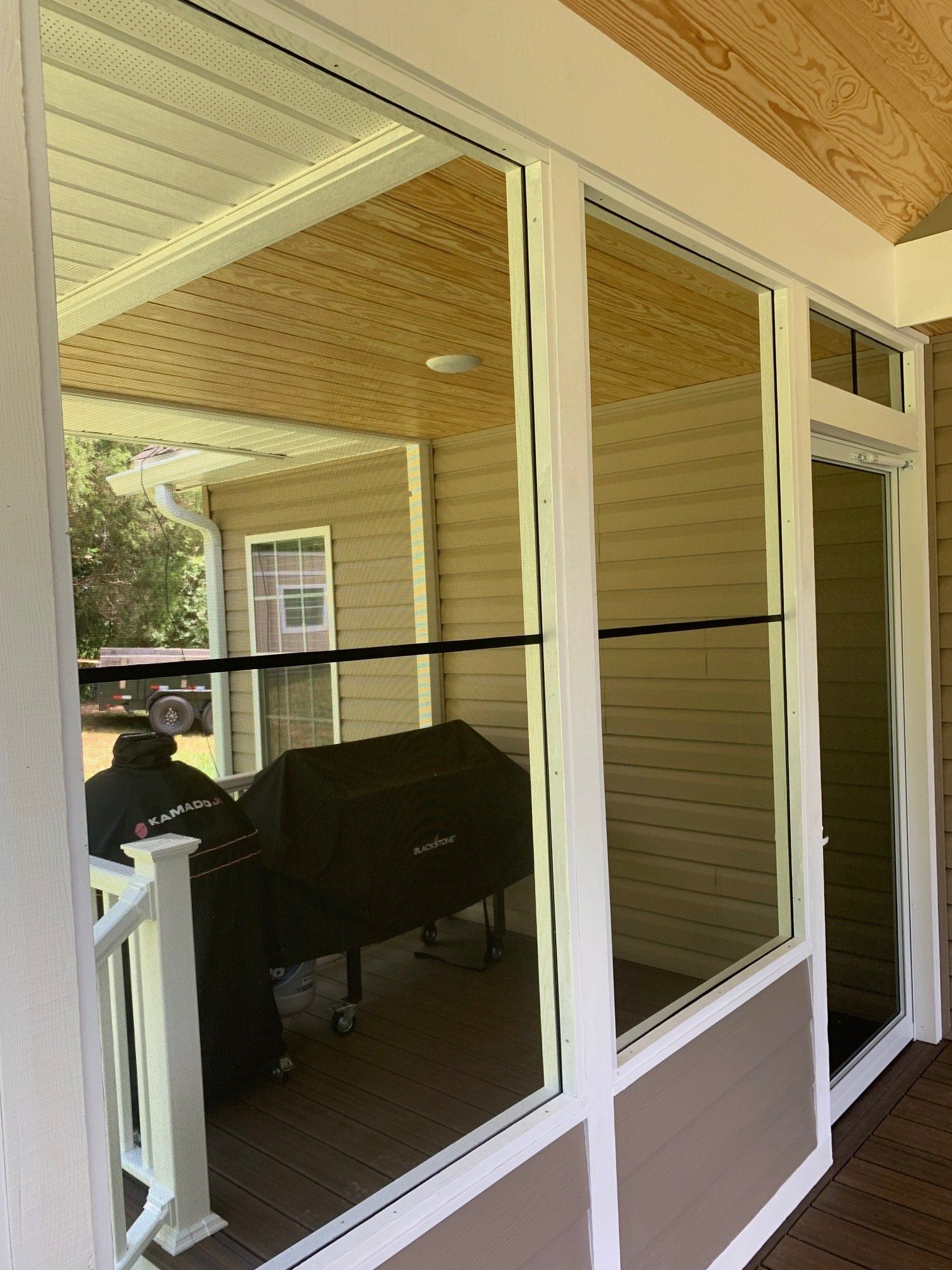 A screened in porch with a grill and a man sitting on the porch.