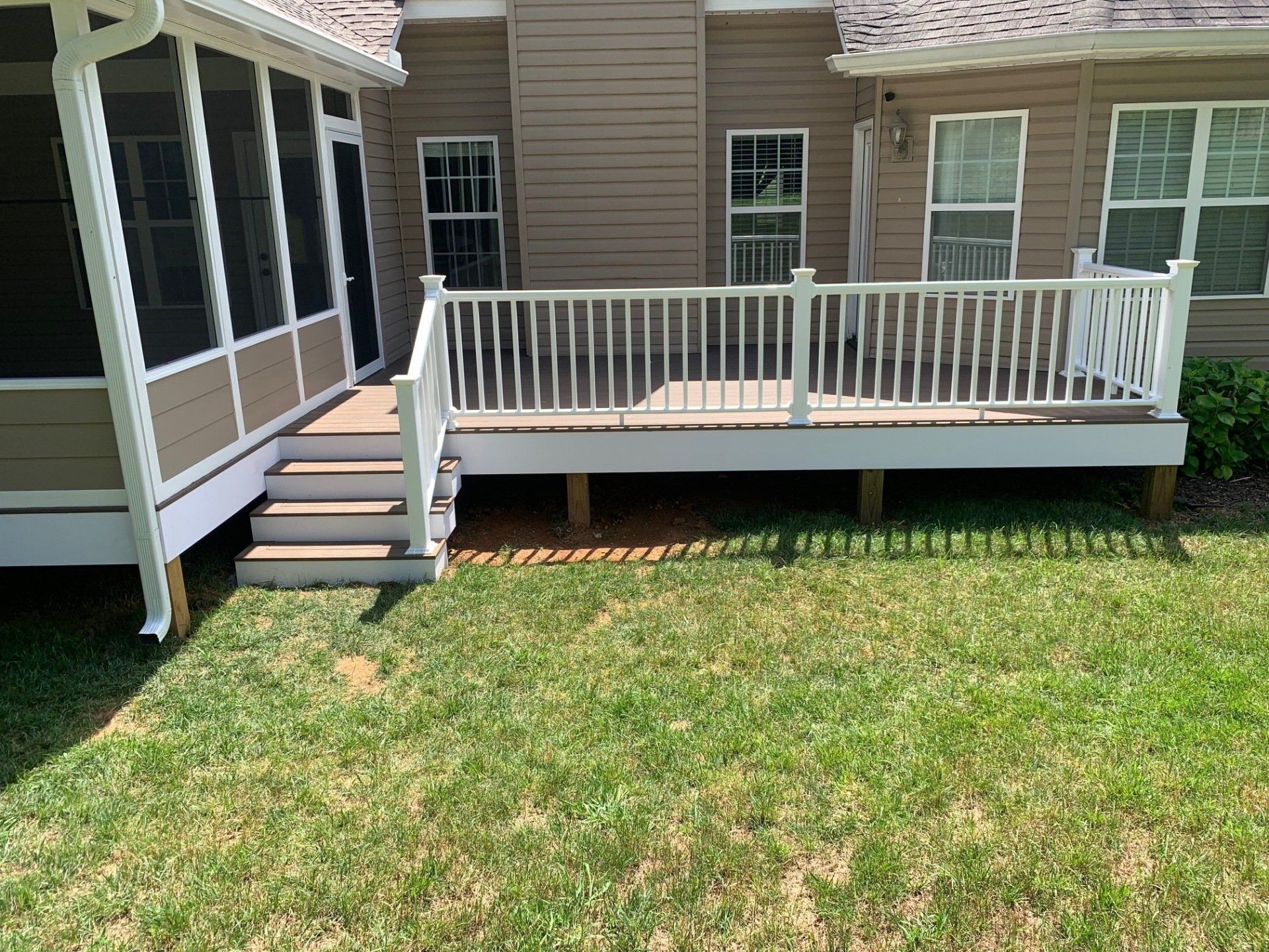 A screened in porch with a deck and stairs in front of a house.