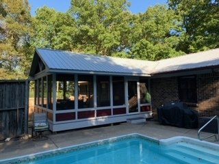 A screened in porch next to a swimming pool