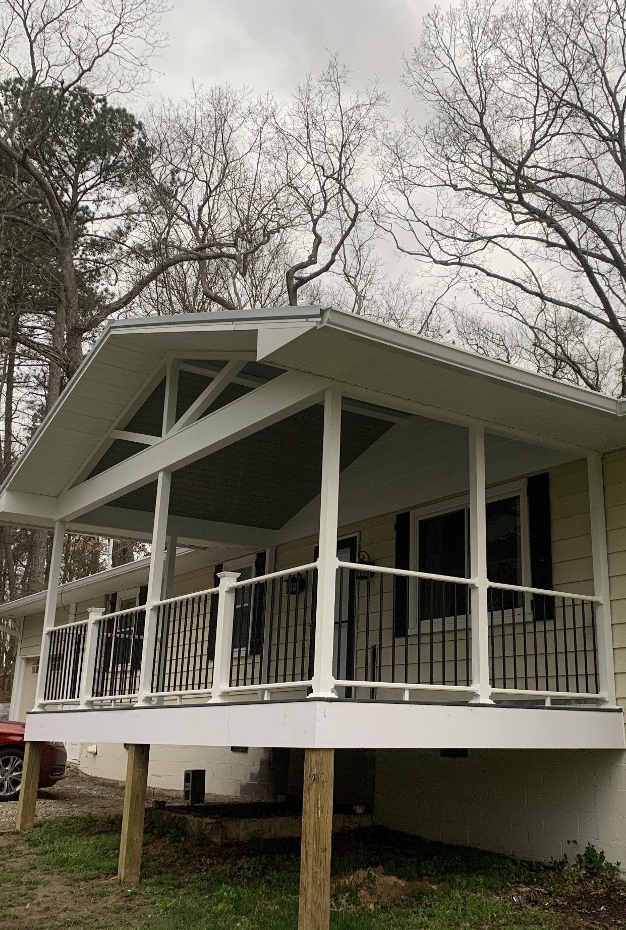 A small white house with a large porch and trees in the background.