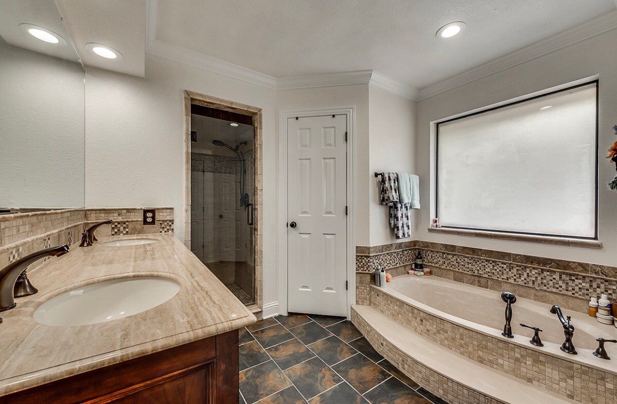 A bathroom with a sink , tub and mirror.