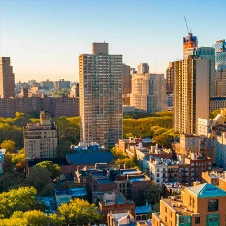 City skyline with various tall buildings, trees, and blue sky in the background during daytime.