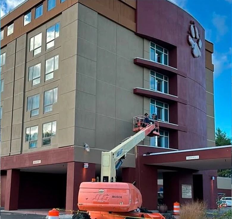 Building exterior with an orange lift. People working on the facade. Brown and beige colors. Paw print logo.