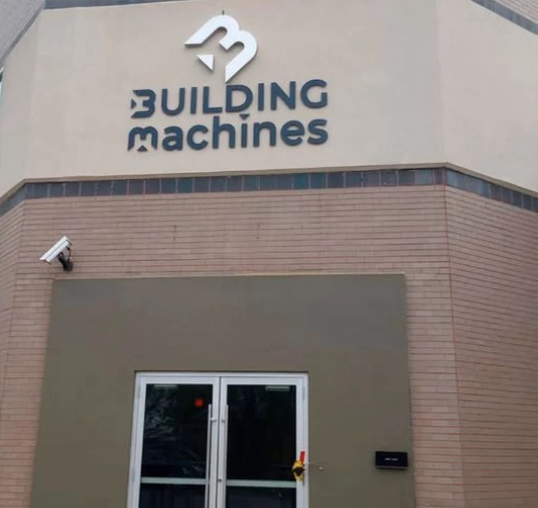 Building Machines storefront with logo above a door and security camera.