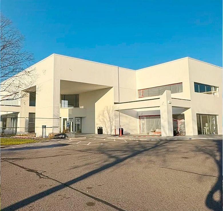 White modern building with large overhang entrance. Sunny day with clear blue sky.