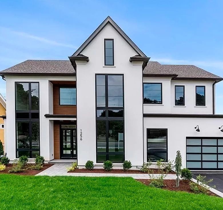 Modern white two-story house with black-framed windows, dark garage door, and a green lawn.