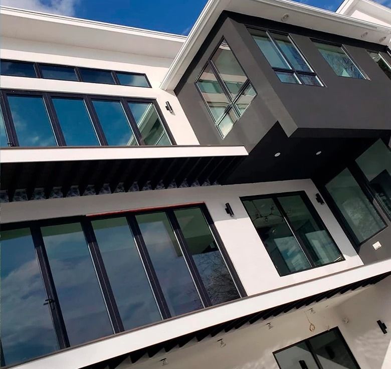 Modern two-story building with white and black exterior, large glass windows, and a blue sky backdrop.