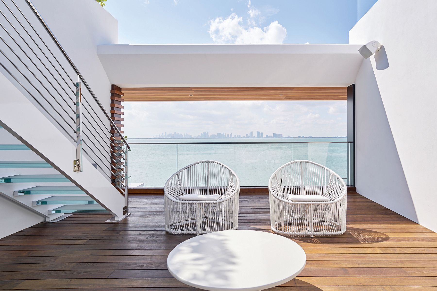 A balcony with two chairs and a table overlooking the ocean.