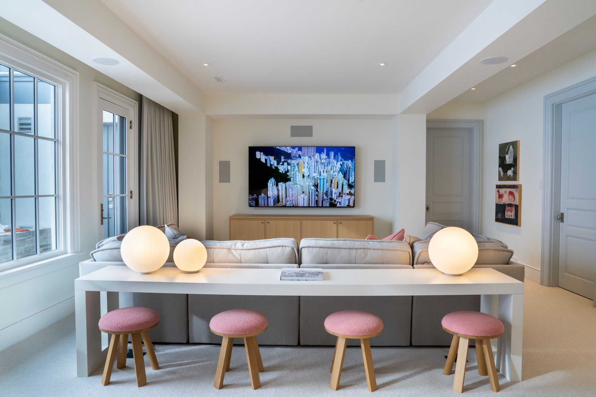 A living room with a couch, table, stools and a flat screen tv.