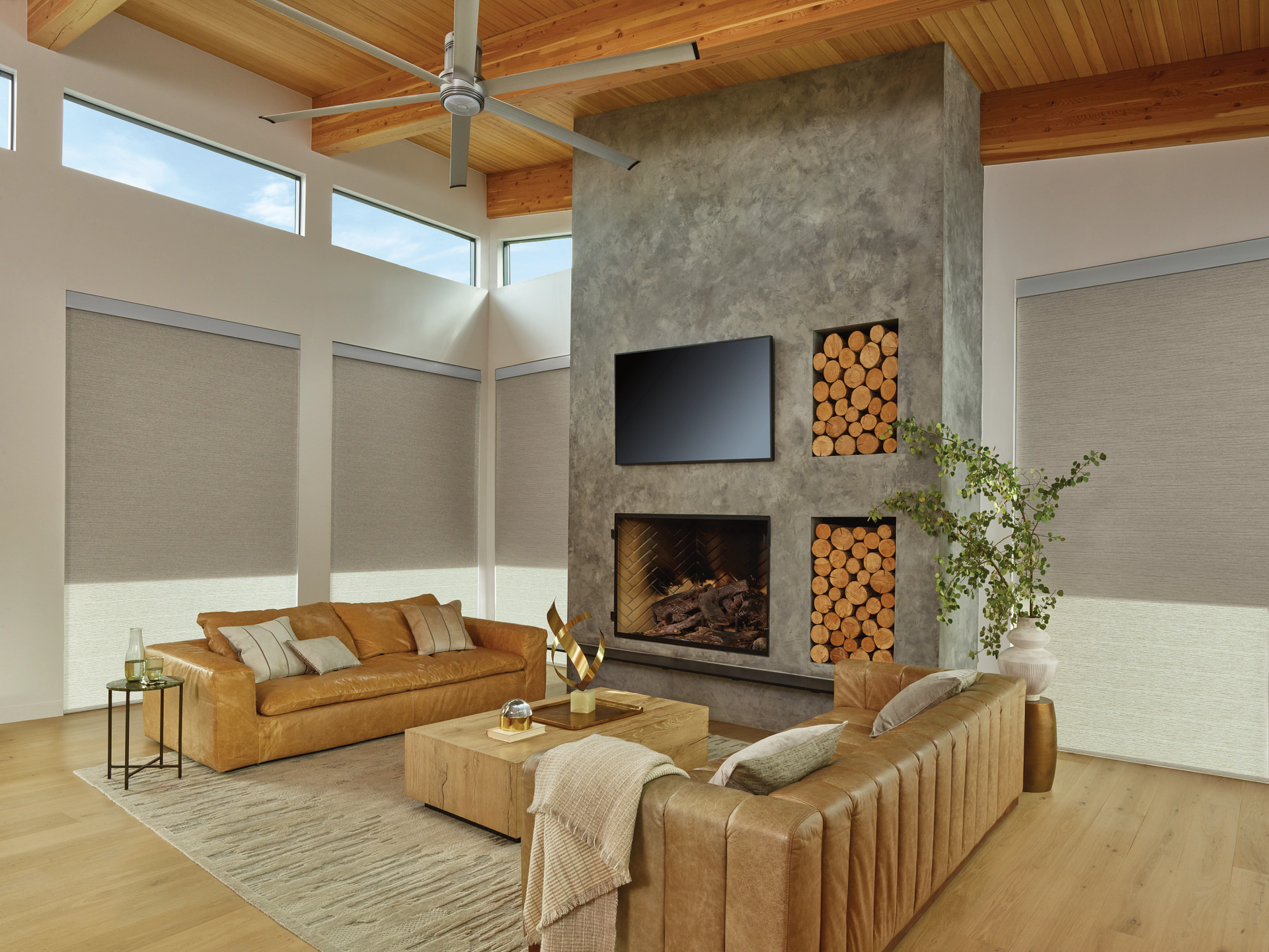 A living room with a couch , fireplace , television and ceiling fan.
