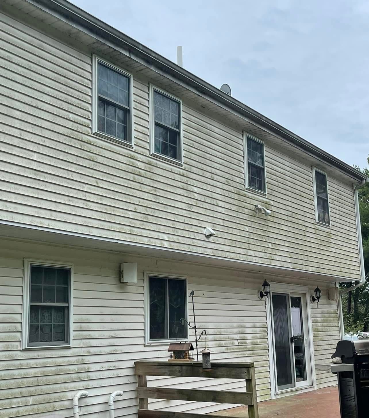 A two-story house exterior with light-colored horizontal siding that appears dirty and in need of cleaning.