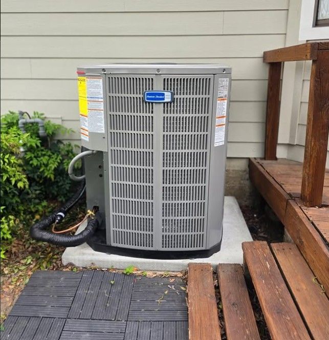 Outdoor air conditioner unit beside wooden porch steps and a house wall
