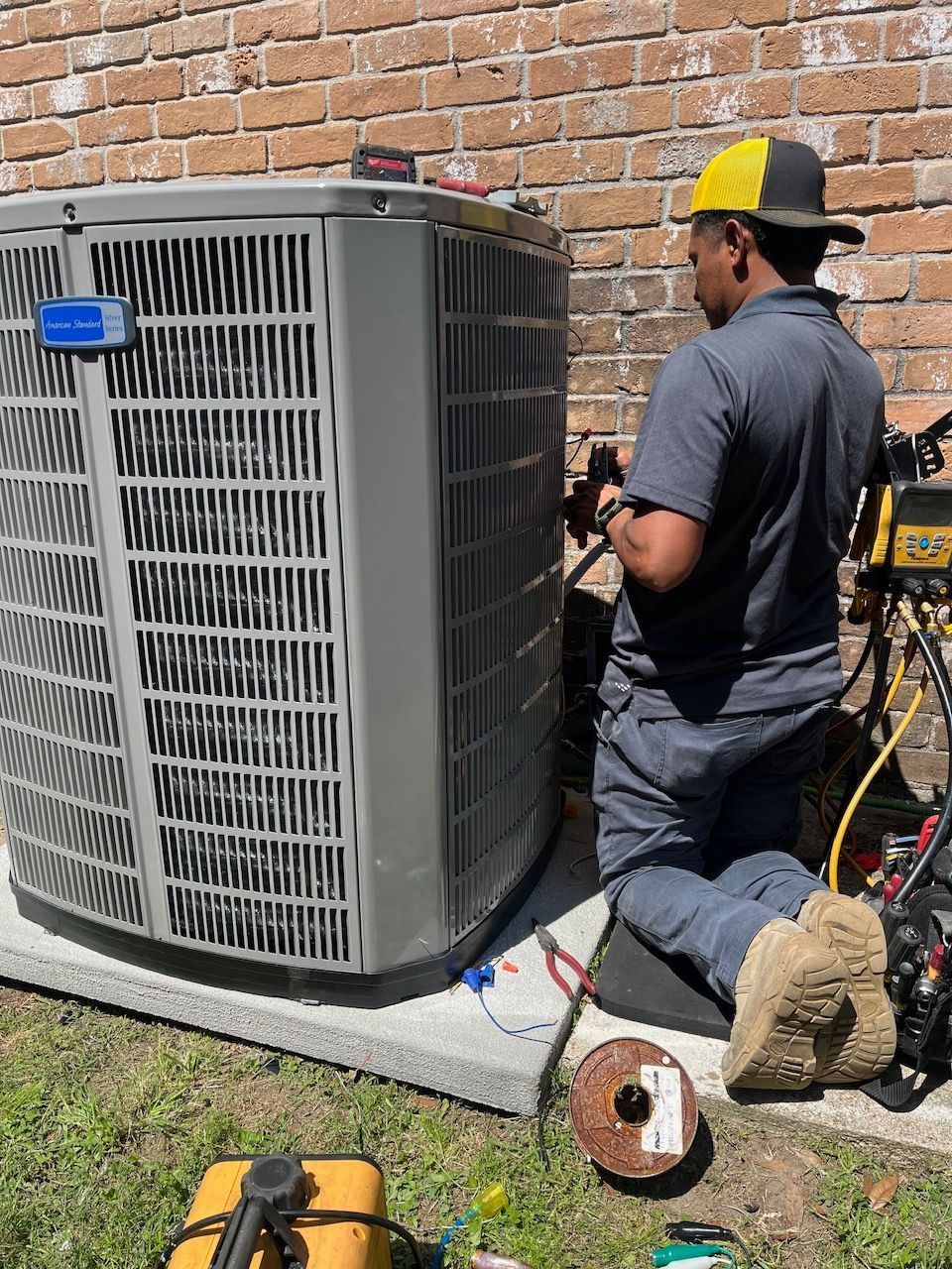 Repairman working on an outdoor HVAC unit while performing a service or maintenance check