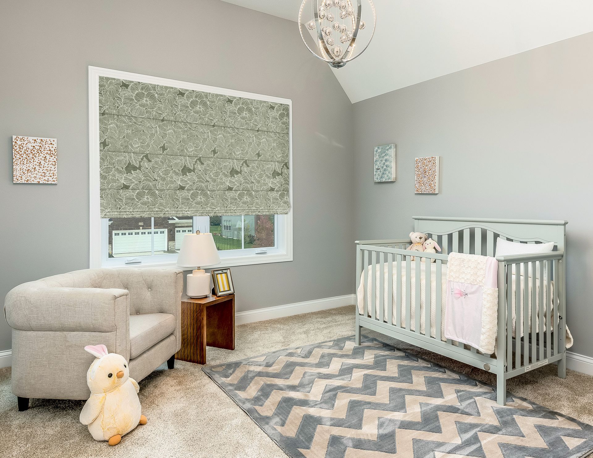 Cozy nursery with gray walls, crib, rocking chair, plush rug, and patterned curtains