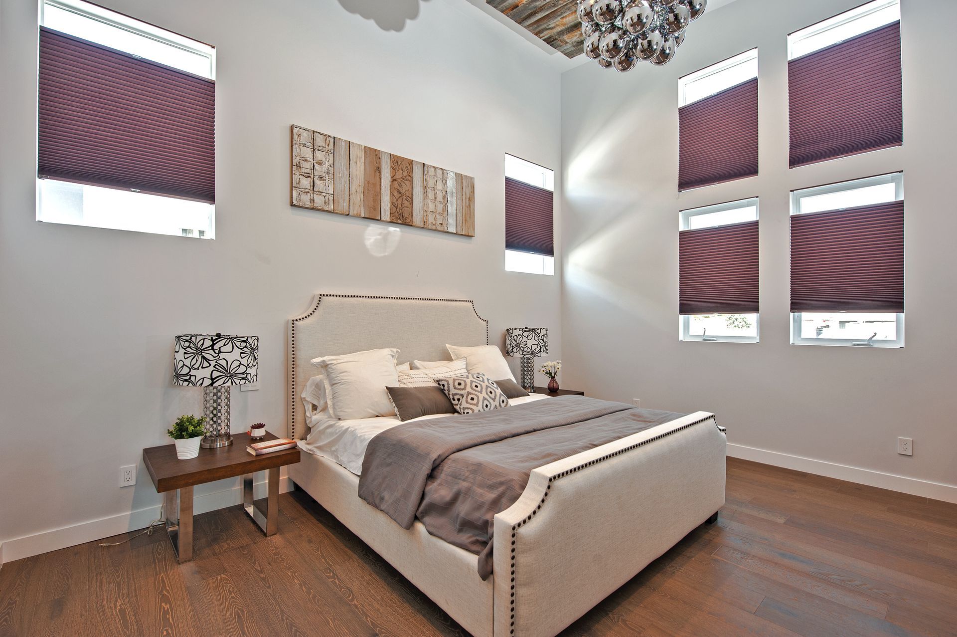 Bright bedroom with a bed, side table, wall art, and purple window shades in a modern home.