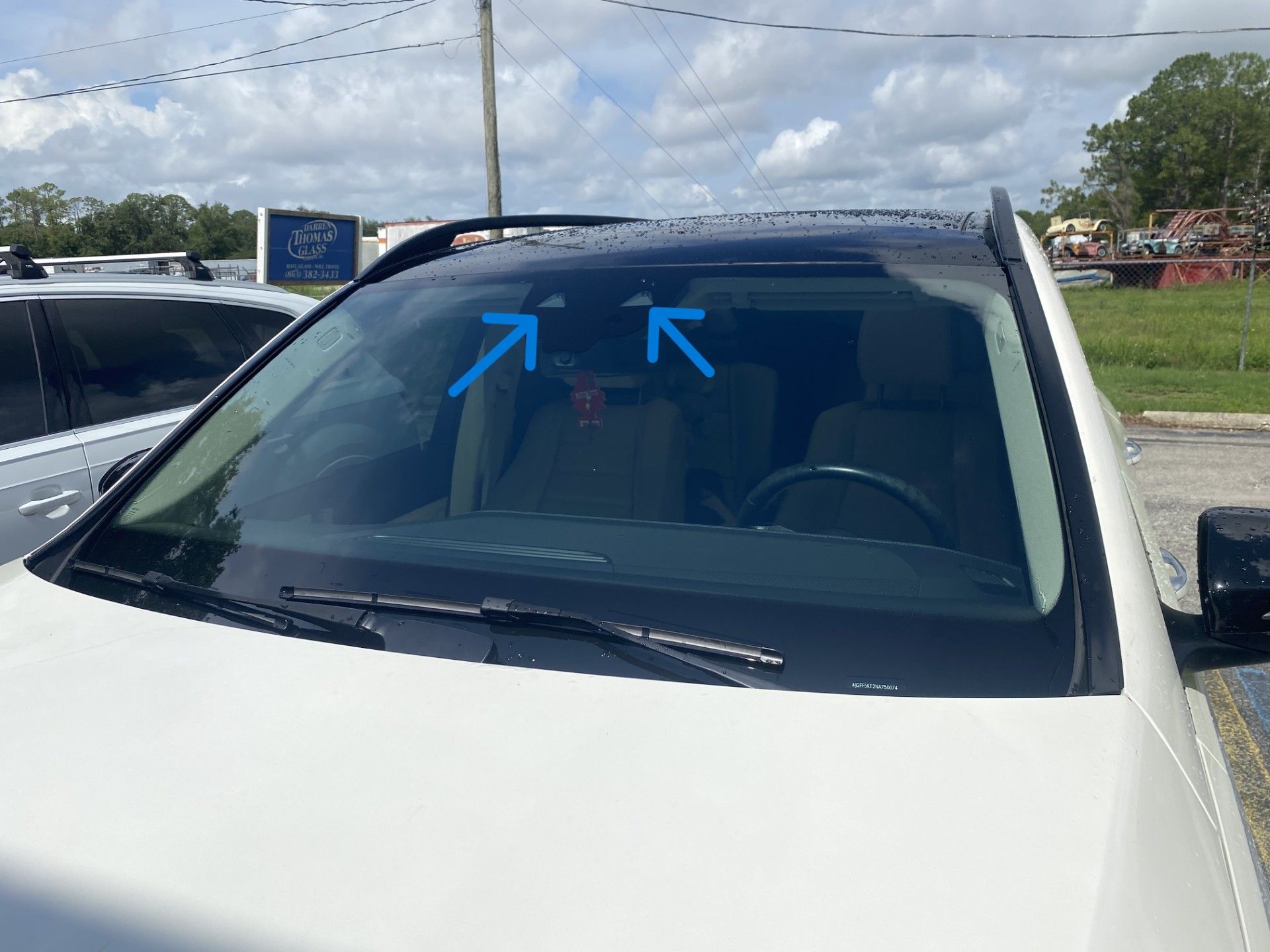 White SUV windshield with blue arrows pointing at the top center area
