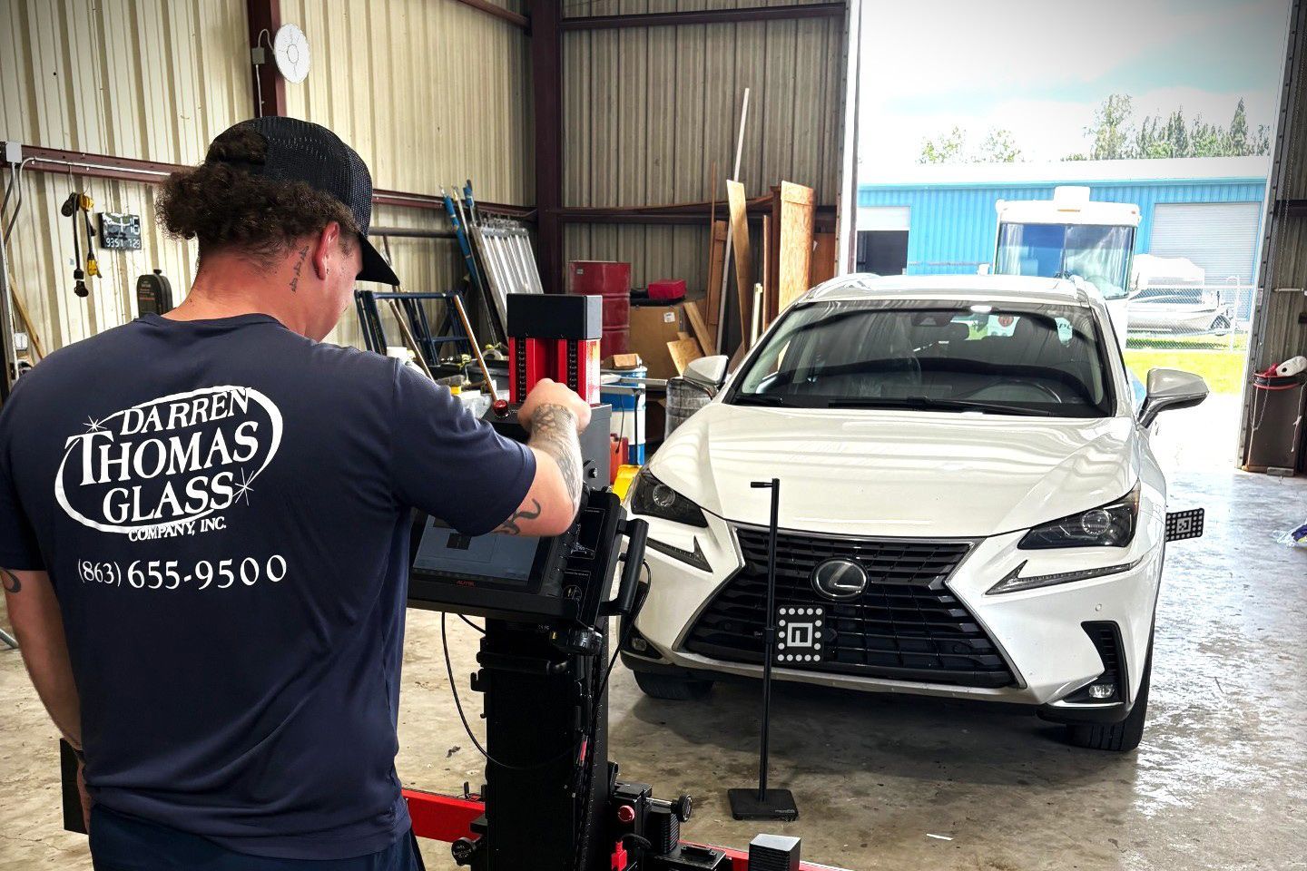 Technician using a machine to service a white sedan in a garage workshop