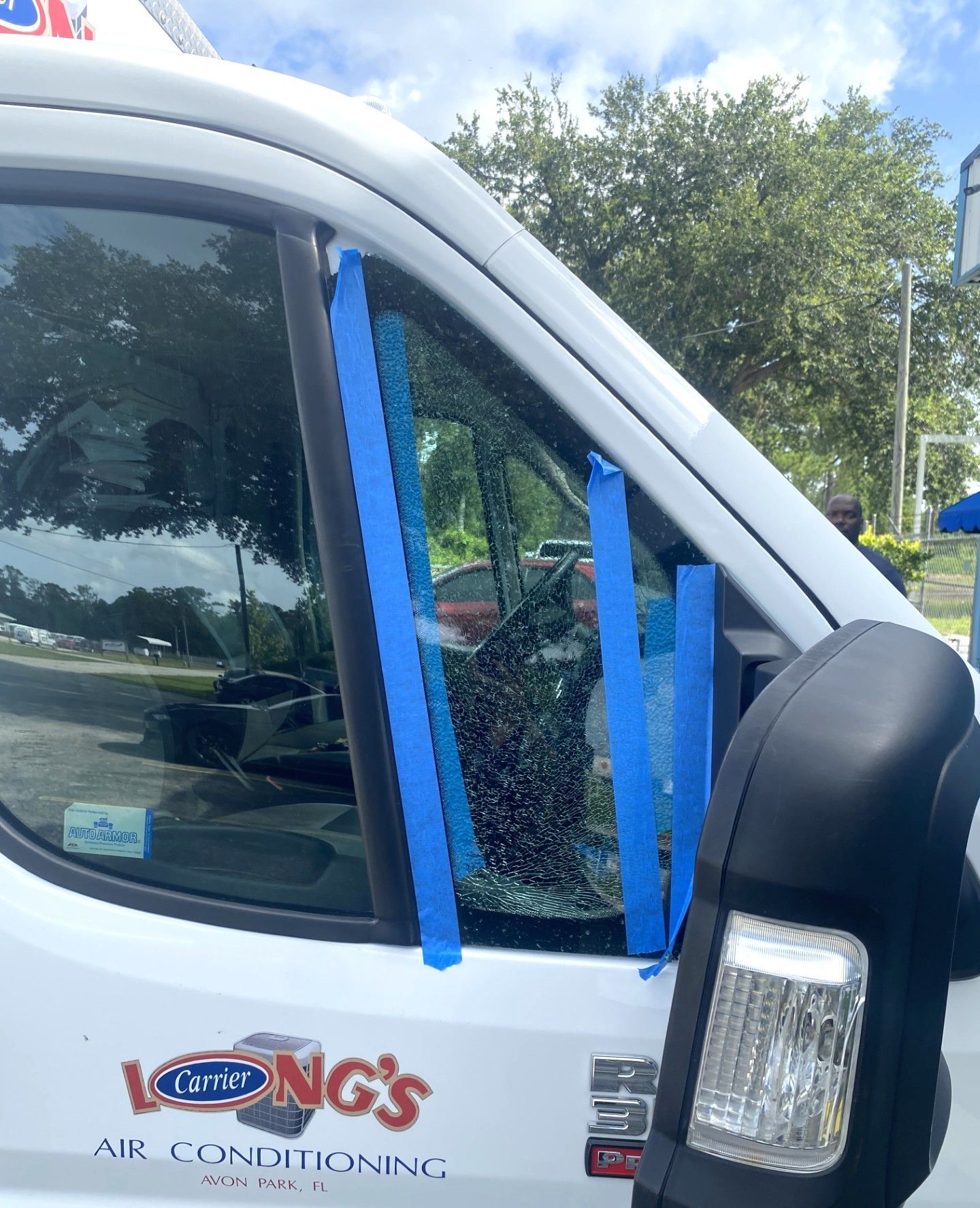 White utility truck with blue tape over a shattered passenger-side window