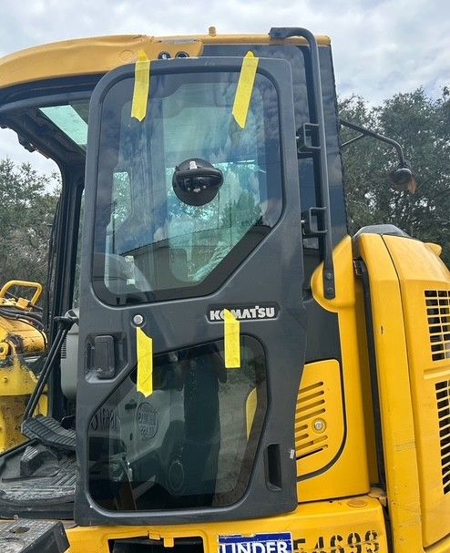 Yellow construction vehicle cab with black door and tinted window, viewed from the side.