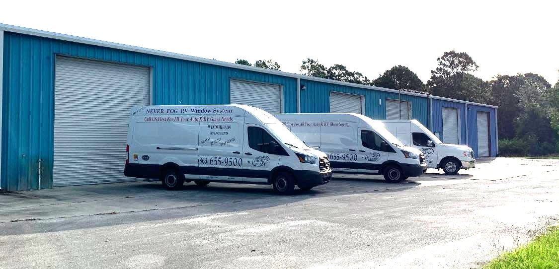 White delivery vans parked outside a blue industrial building with a large garage door
