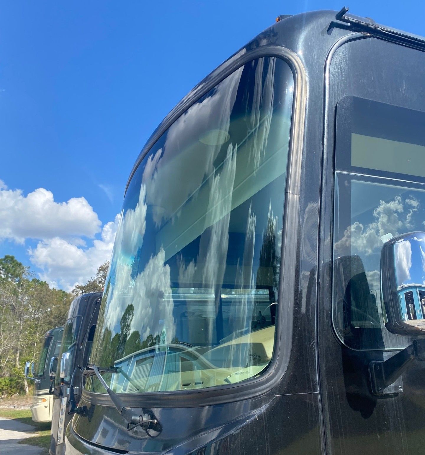 Technician performing glue-in windshield installation on RV coach at Darren Thomas Glass Company in Sebring FL