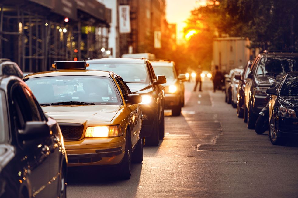 Yellow taxi in evening traffic on a city street at sunset