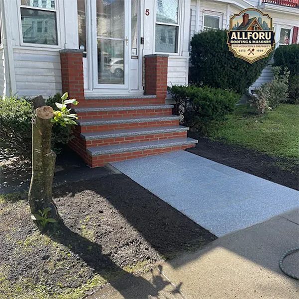 Exterior view of a house with brick steps and a concrete ramp leading to the front door.