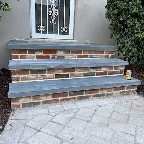 Brick steps with gray stone treads leading to a white door. A can sits on a step.