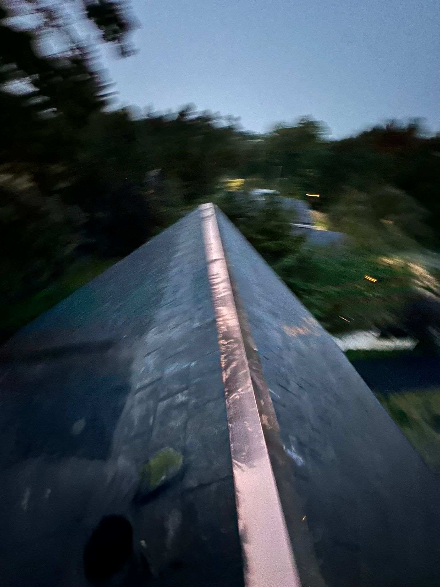 Close-up view of dark gray slate roof tiles, textured with sunlight reflections.