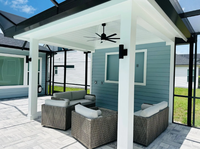 Patio with seating area and blue wall, under a white structure with ceiling fan.