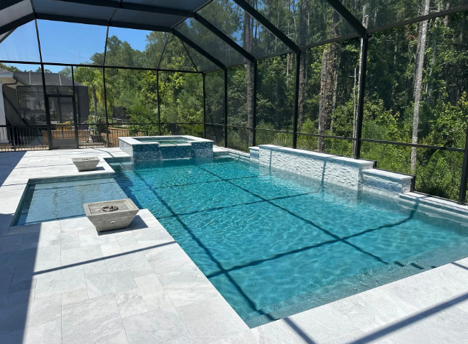 Pool area with rectangular pool, spa, fire pits, and screened enclosure, surrounded by a forest.