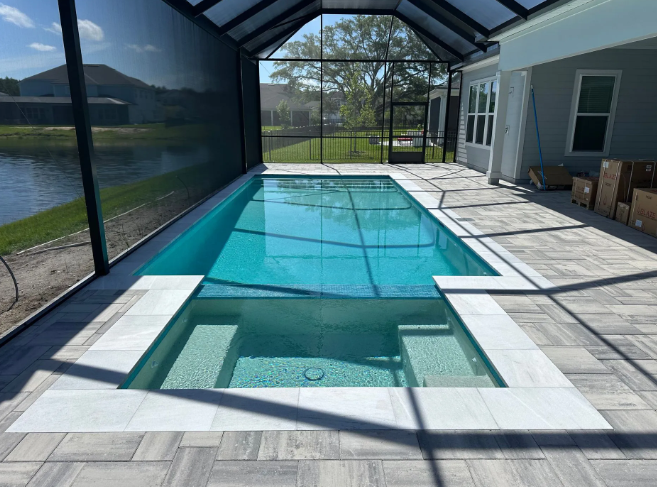 Pool with spa, screened enclosure. Blue water, light stone patio.