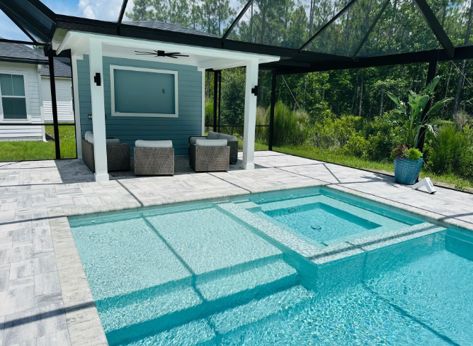 Pool area with blue water, spa, covered seating with a TV, and surrounding nature.