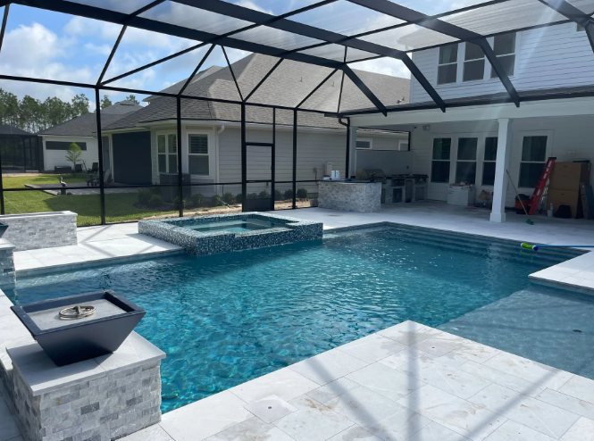A turquoise pool with a spa, under a screened enclosure, surrounded by a white patio and a house.