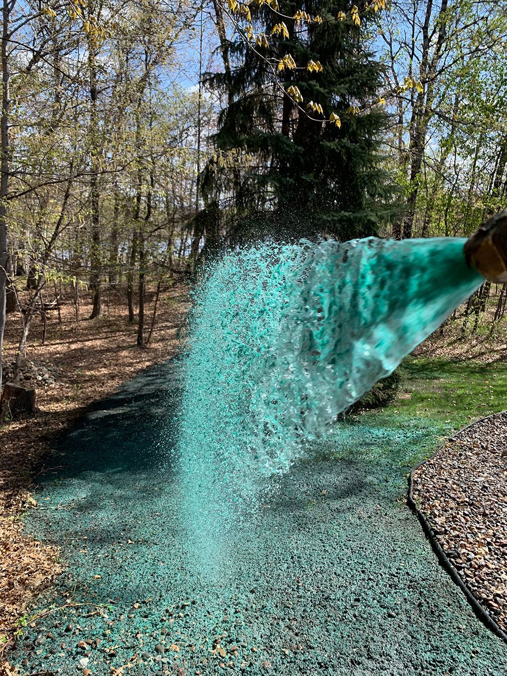 A person is spraying green on a lawn