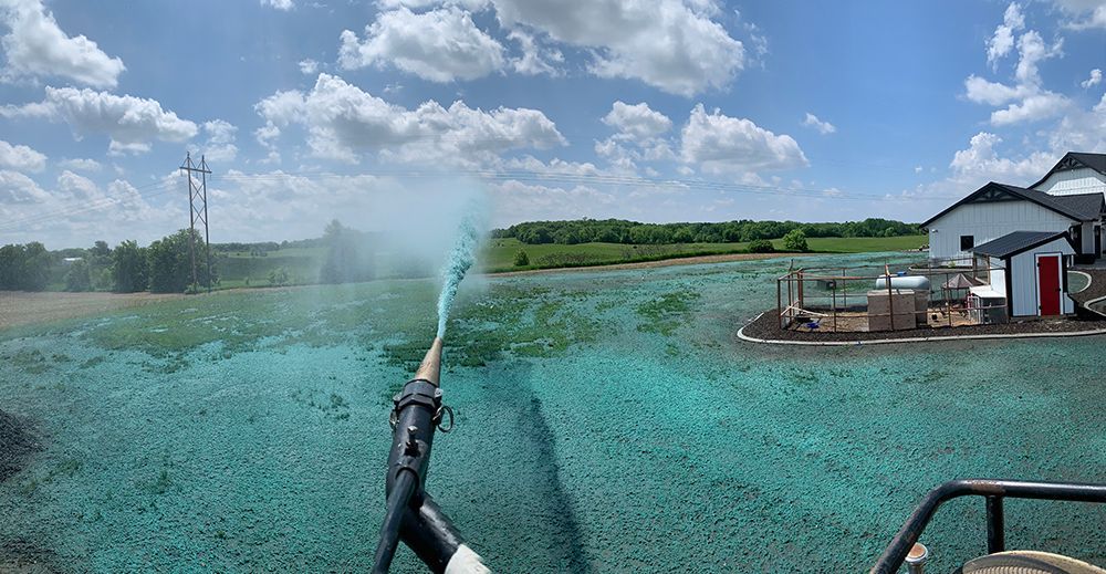 A person is spraying a field with a hose