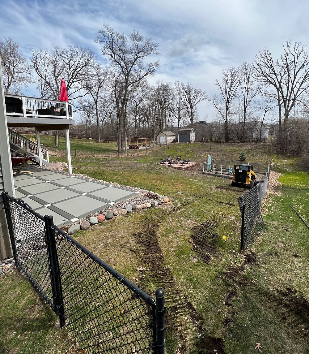 A backyard with a fence and a patio in the middle of it