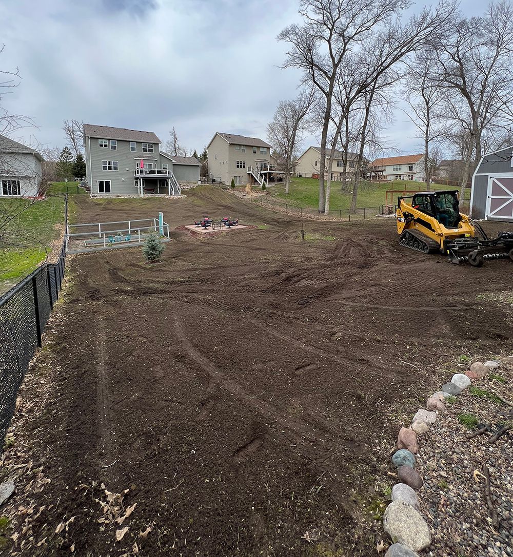 A bulldozer is working on a dirt field in front of a house