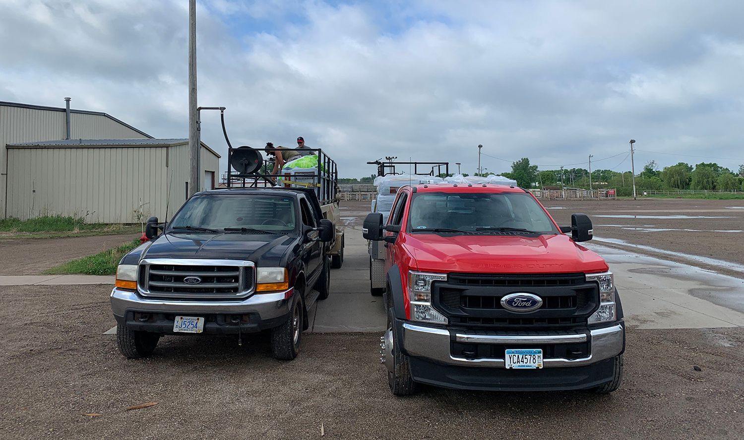 Two trucks are parked next to each other on a gravel road