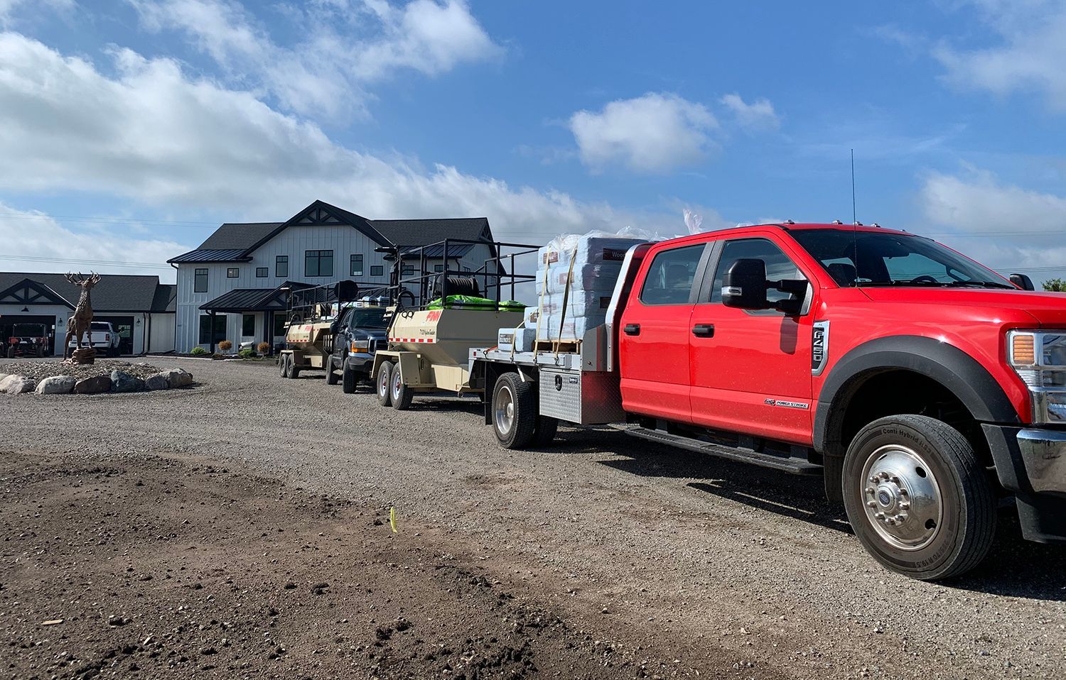 A red truck is parked in a gravel lot next to a house