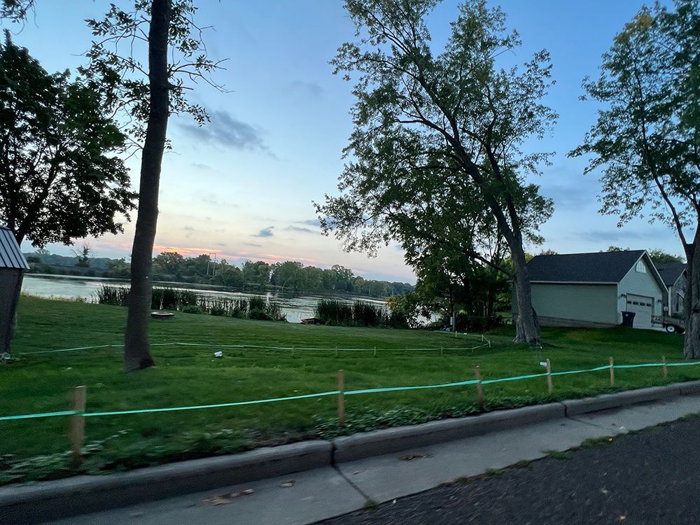 A fenced in yard with a house and a lake in the background