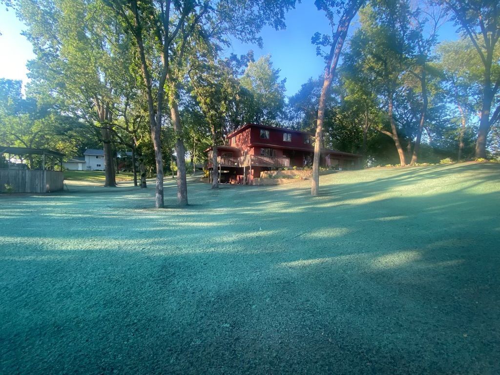 A red house sits in the middle of a lush green field