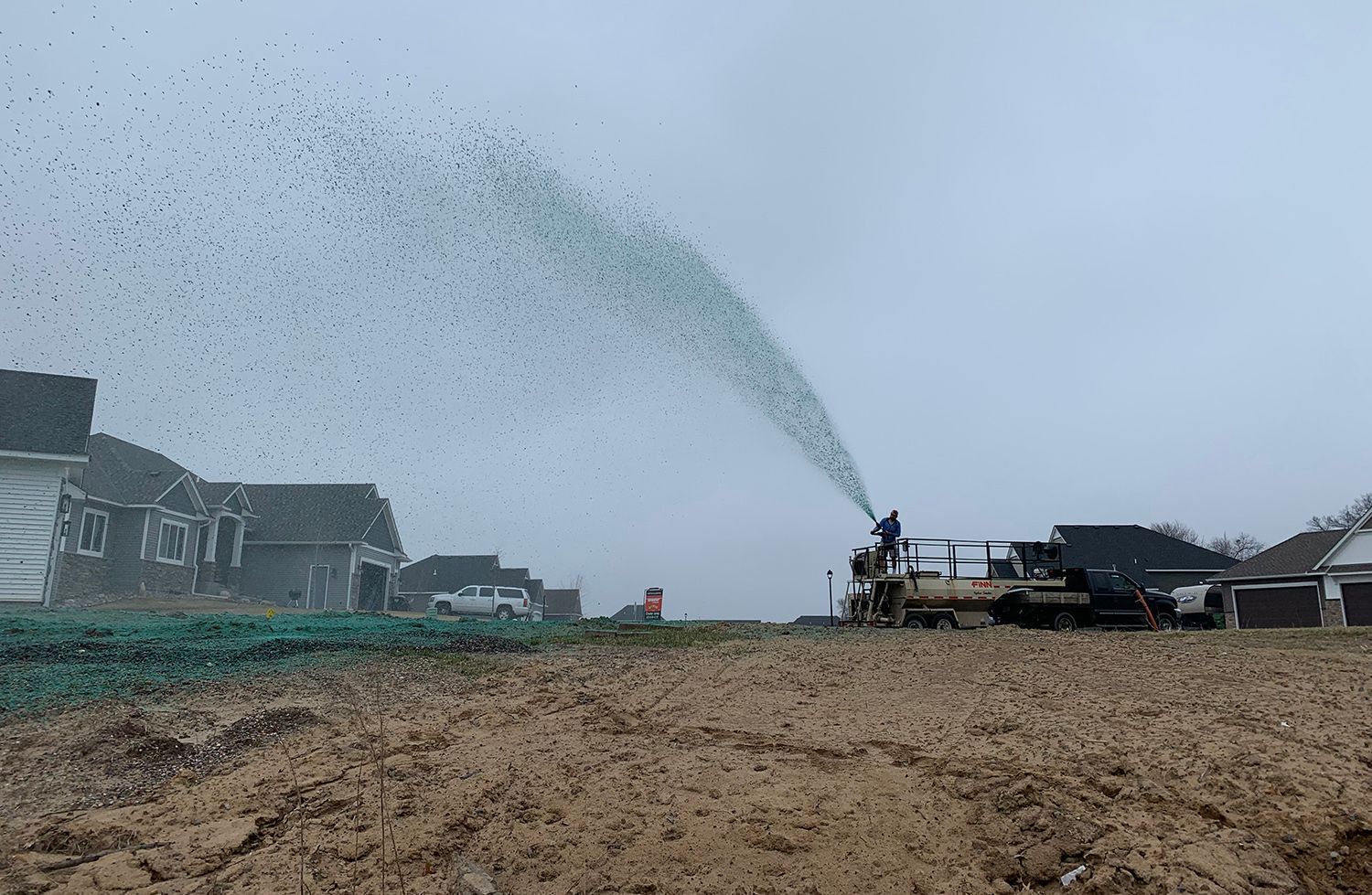 A truck is spraying green fertilizer on a dirt field