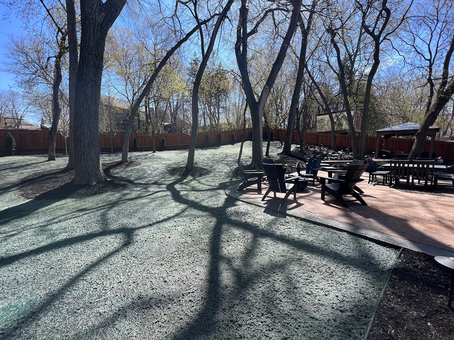 A patio area with tables and chairs in a park surrounded by trees