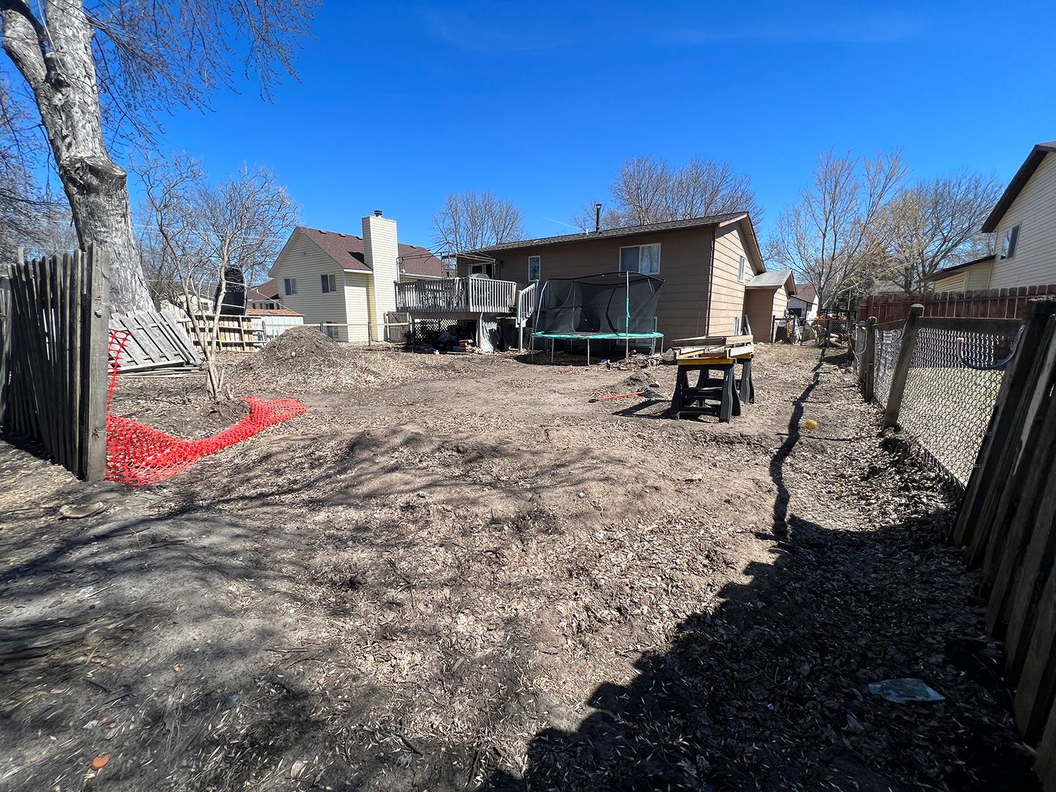 A backyard with a fence and a house in the background