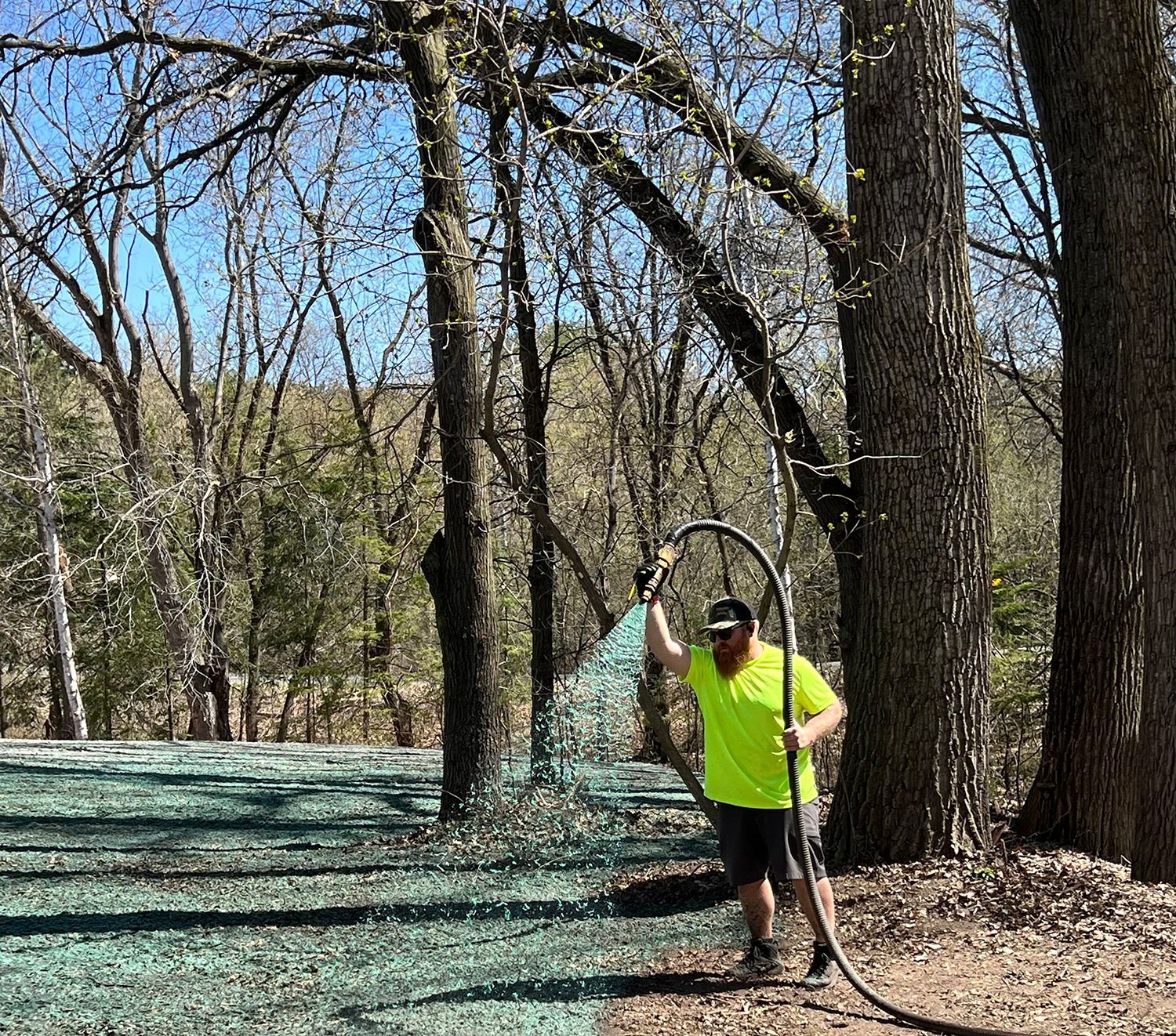 A man is spraying grass with a hose in the woods