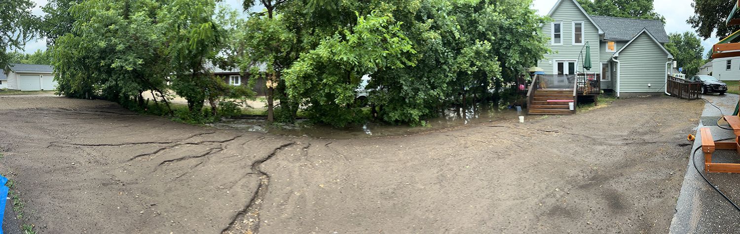 A yard with a house in the background and a picnic table in the foreground