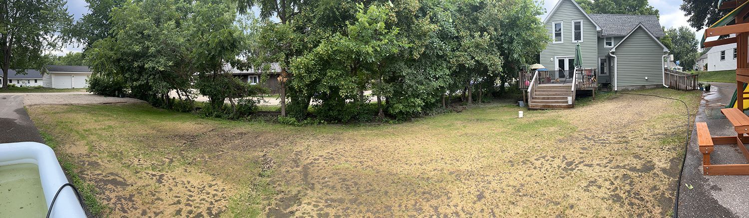 A panoramic view of a yard with a house in the background