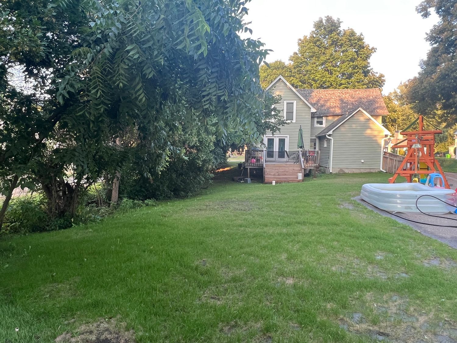 A large yard with a house and a pool in the background
