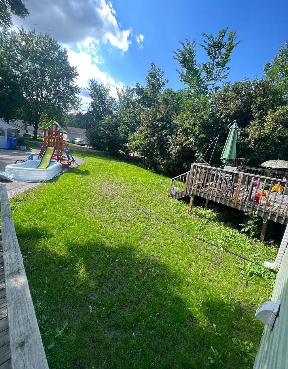 A lush green yard with a playground and a deck